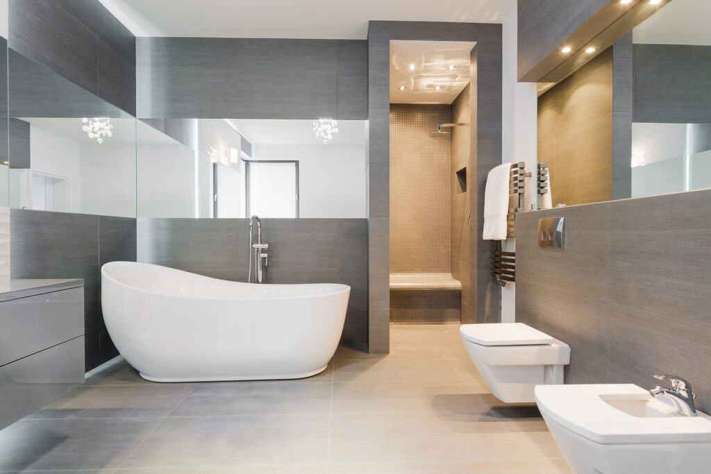 Luxe badkamer met vrijstaand bad, ingebouwde douche, wandtoilet en spiegelwand