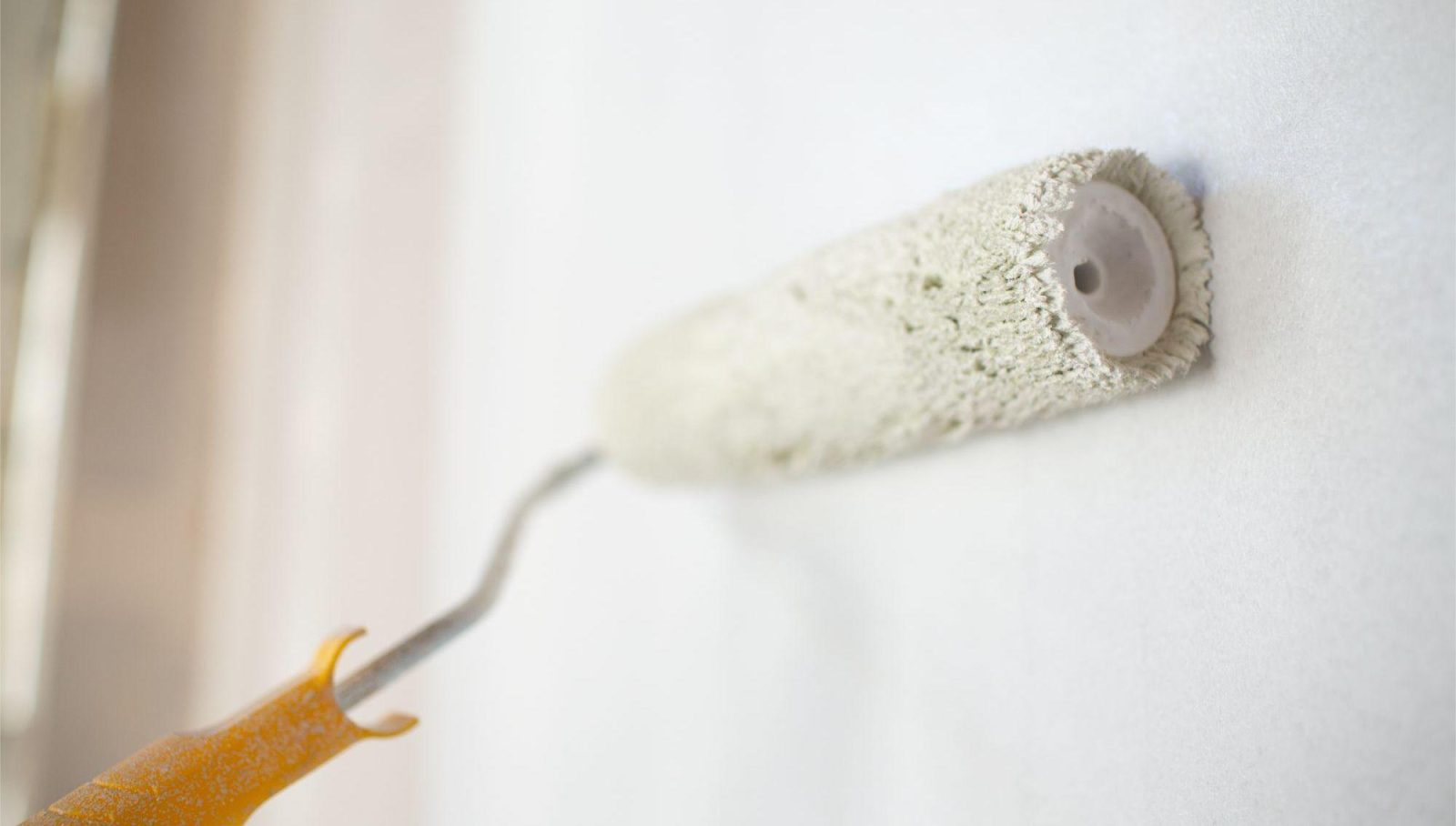 Professioneel schilderwerk: verfrol wordt gebruikt om muur te verven in een renovatieproject